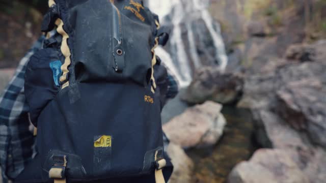 男人徒步旅行在森林和瀑布与旅行背包在假日。视频下载
