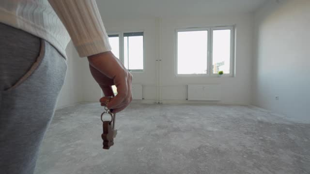 搬进新公寓，女人拿着钥匙走进新公寓，空荡荡的白色房间视频素材