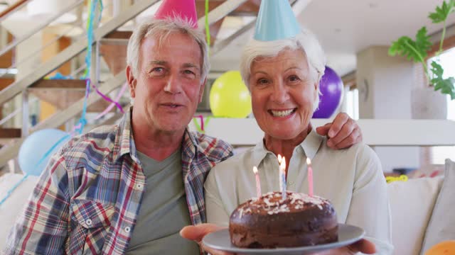 老白人夫妇在家里拿着蛋糕庆祝生日的照片视频下载