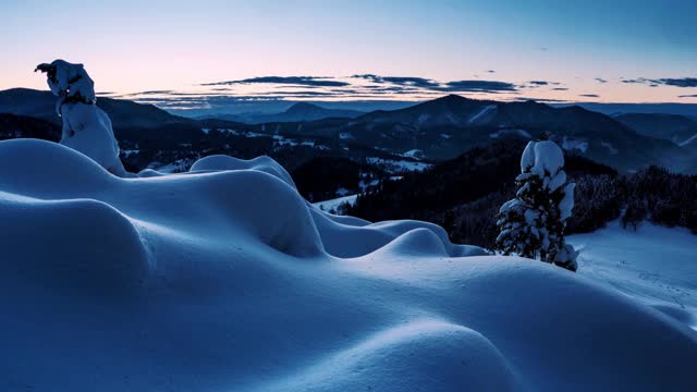 蓝色的日出早晨在野生的冬季山脉自然与冰冻雪林景观视频下载