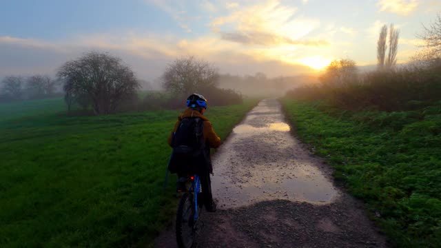 跟着一个骑着自行车走向雾蒙蒙的日出的小男孩视频下载