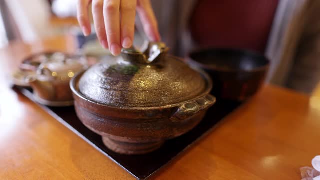 在日本餐馆里，一名年轻女子拿着一个陶罐的盖子视频素材