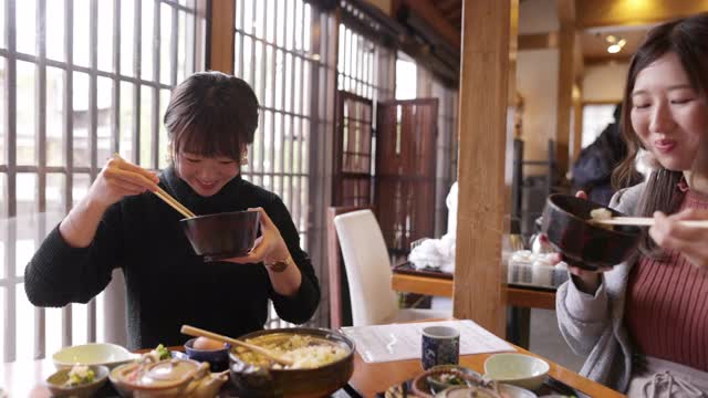 年轻女性在日本餐馆吃“Donabe Gohan”健康的日本食物视频下载