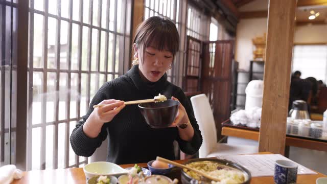 年轻女性在日本餐馆吃“Donabe Gohan”健康的日本食物视频素材