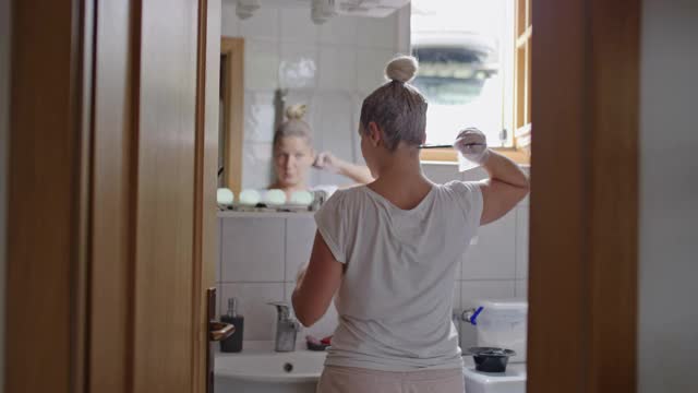 一个女人在浴室的镜子前染头发视频素材