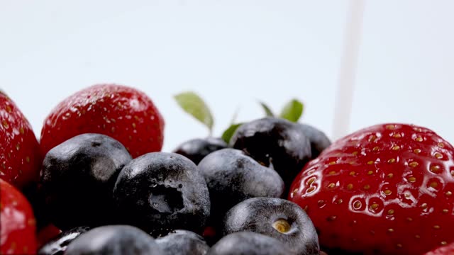 将酸奶或牛奶倒在有机新鲜蓝莓和草莓上。奶油浆果。有机素食的概念。特写,4 k分辨率。视频下载