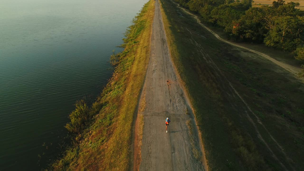 无人机拍摄到一个人在湖边跑步视频素材
