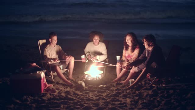 朋友们在晚上围着篝火玩视频素材