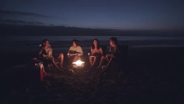 朋友们在晚上围着篝火玩视频素材