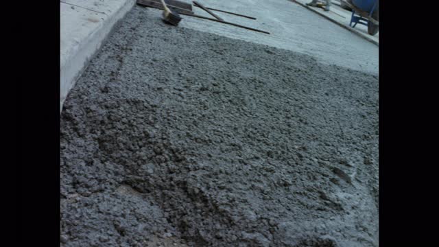 当建筑工人在街上工作时，倾斜水泥搅拌机在建筑工地浇注混凝土的镜头视频下载