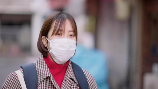 年轻女子戴着防护口罩走在街上视频素材