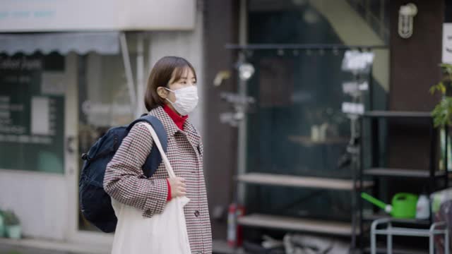 年轻女子戴着防护口罩走在街上视频素材