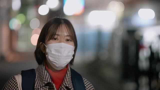 在冬天的晚上，年轻女子戴着防护面罩走在街上视频素材