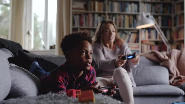 母亲和儿子在客厅玩电子游戏时的手持镜头视频下载