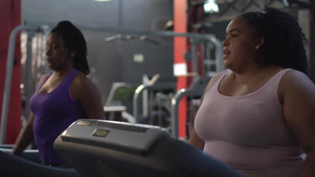 在健身房跑步机上聊天的女人视频素材
