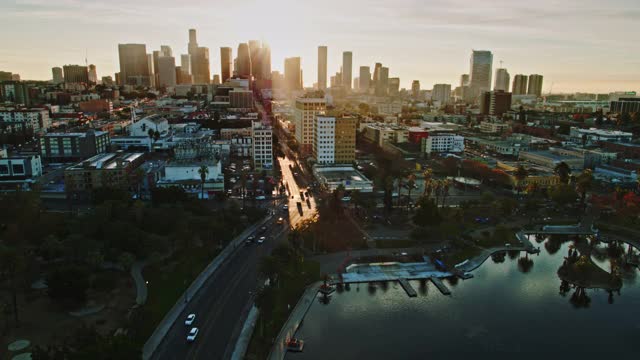 从空中拍摄的旭日照耀着麦克阿瑟公园的威尔希尔大道视频素材