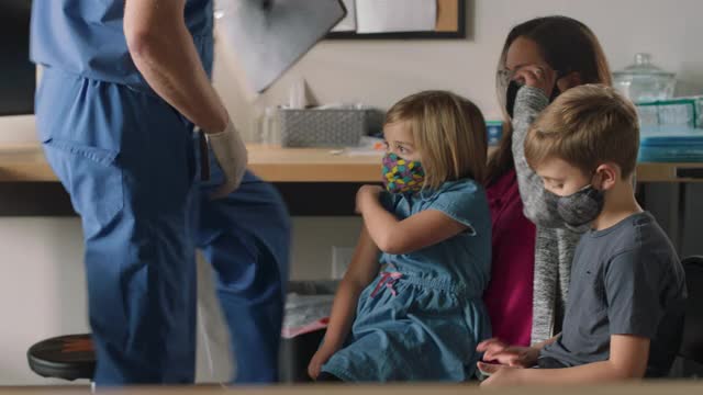 与家人坐在医疗机构接受COVID-19疫苗接种的合作小女孩视频下载