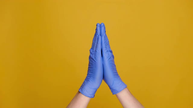 男性双手在医疗防护手套显示大尺寸的姿态，显示一些宽，孤立的黄色工作室背景与广告复制空间。肢体语言的概念视频素材