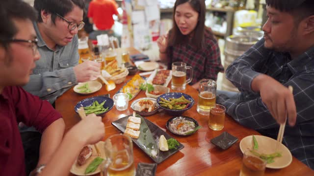 一群亚洲工薪族在日本居酒屋用食物和啤酒吃饭欢呼视频素材