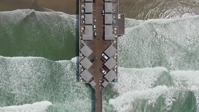 空中翻转的太平洋海滩码头与轻微倾斜的海浪，冲浪者，和海藻-圣地亚哥，加利福尼亚视频下载