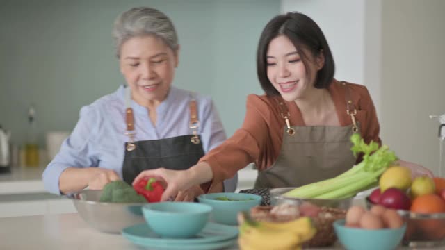 亞洲華人美麗的女人和她的母親準備做飯為家人在廚房柜臺視頻下載