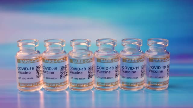 一套COVID-19疫苗瓶和注射注射器，背景为抽象的蓝色。标记SARS-CoV-2对抗冠状病毒视频素材