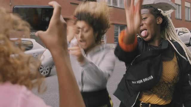 一名女子用智能手机拍摄欢快的朋友在城市街道上跳舞视频下载