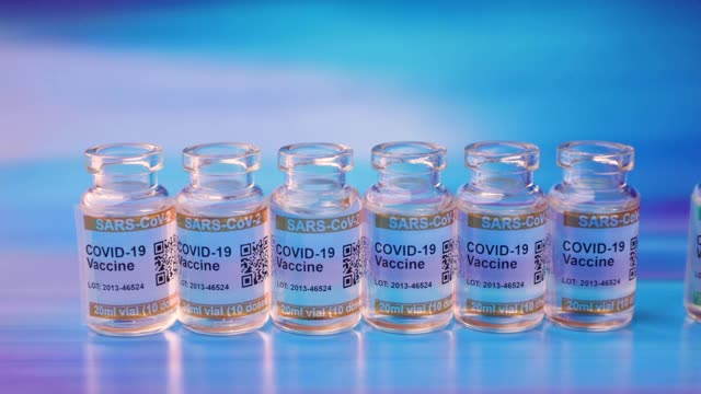 蓝色抽象背景的COVID-19疫苗瓶。标记SARS-CoV-2对抗冠状病毒。手戴防护手套拿起注射器和小瓶视频下载