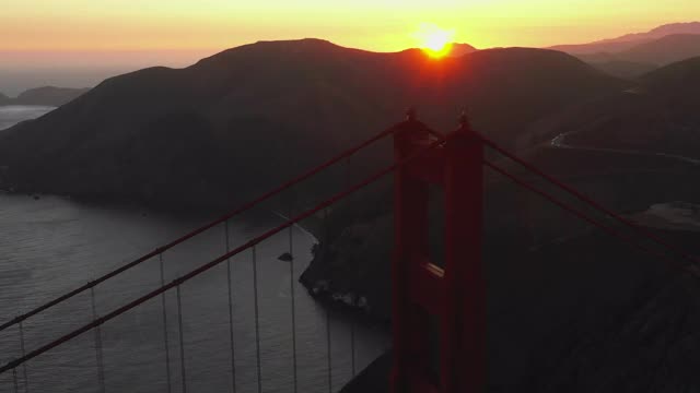 空中平移拍摄的著名的金门大桥由山脉对天空，无人机飞过流行的地标日落-旧金山，加利福尼亚视频素材
