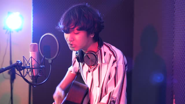 年轻男歌手录制音乐与吉他在工作室，录音室概念视频下载