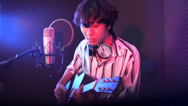 年轻男歌手录制音乐与吉他在工作室，录音室概念视频下载