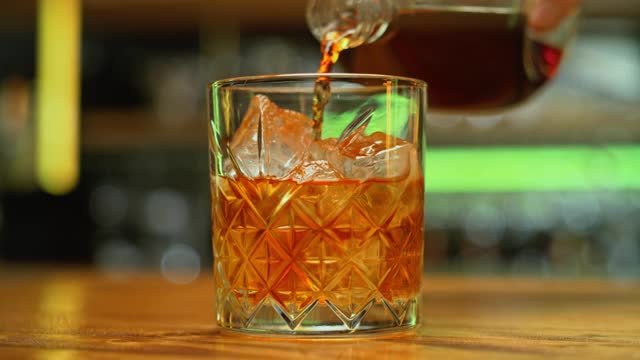 将SLO MO DS威士忌倒入加冰块的岩石杯中视频下载