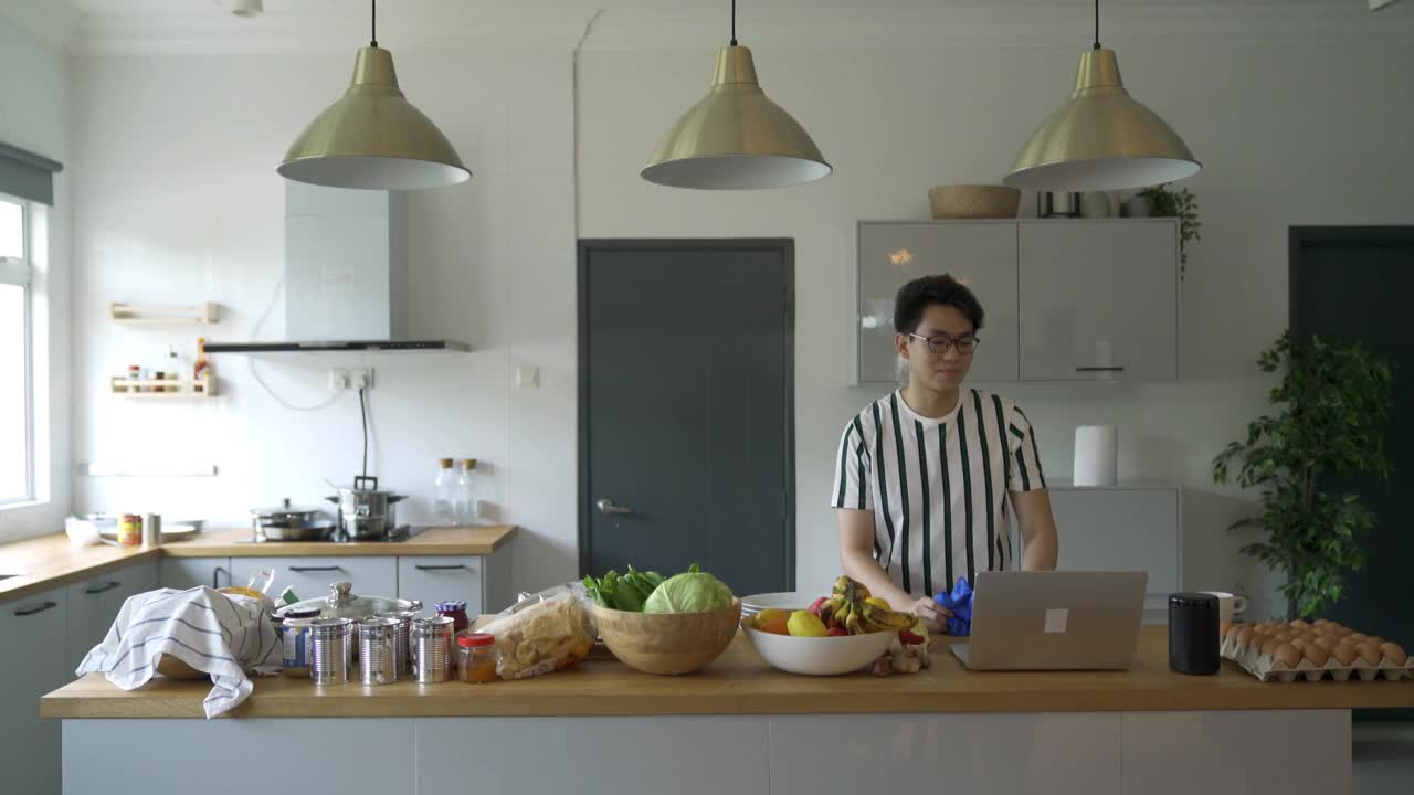 一名亚裔中国男子在家里洗碗的时候通过视频会议和网友聊天视频下载