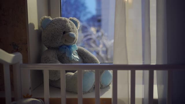 窗外飘着雪花，婴儿床和玩具熊视频素材