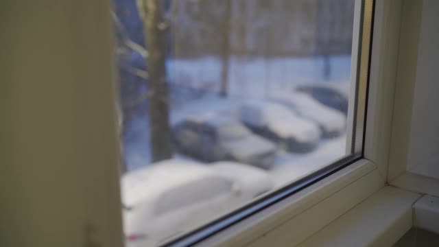 从公寓窗户看到后院飘落的雪花，寒冷的冬天在镇上视频素材