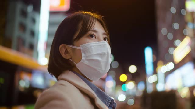 在城市的街道上，一名妇女用面罩遮住她的脸，严肃地看着别处视频素材
