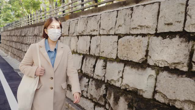 妇女戴着预防疾病的防护面罩，走在街上视频素材