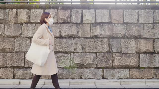 妇女戴着预防疾病的防护面罩，走在街上视频素材