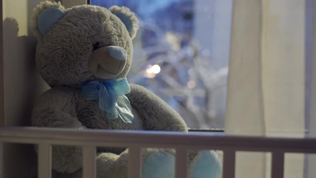 窗外飘着雪花，婴儿床和玩具熊视频素材