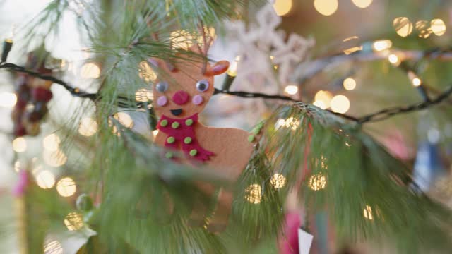 有趣的驯鹿装饰品挂在一棵活的圣诞树上视频下载