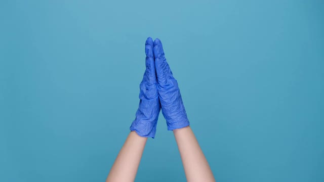 女性双手在医用乳胶手套显示大尺寸的姿态，显示一些宽，孤立的蓝色工作室背景与广告复制空间。肢体语言的概念视频素材