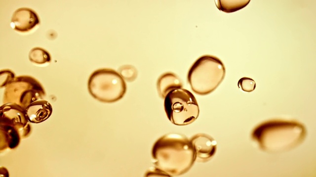 近距離微距和超級慢動作的浮動清澈的水滴在黃色的背景視頻素材