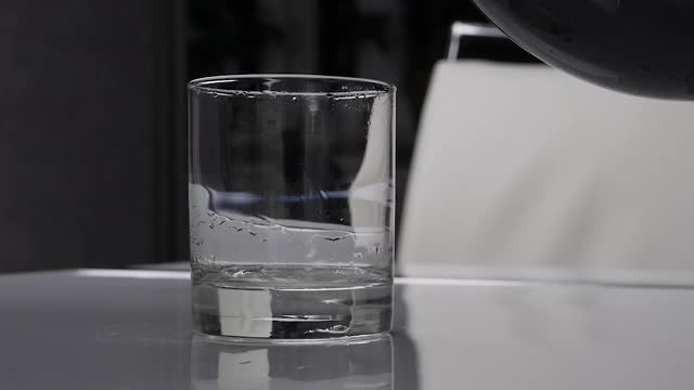 将水倒入有气泡的玻璃杯中，将甜水倒入玻璃杯中。视频素材