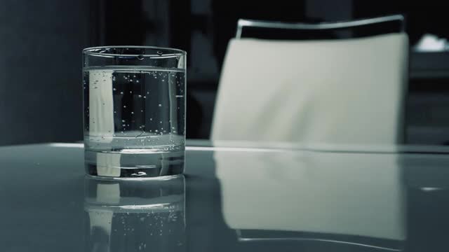 把矿泉水放在透明的杯子里，喝水放在桌子上，气泡矿泉水。视频素材