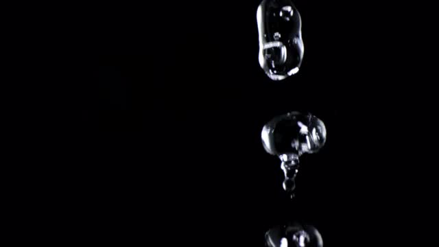 近距离微距和超级慢动作的浮动清澈的水滴孤立的黑色背景视频购买