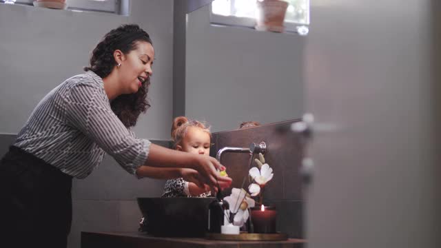 手持拍摄的好玩的母亲和女儿洗玩具在浴室水槽在家里视频素材