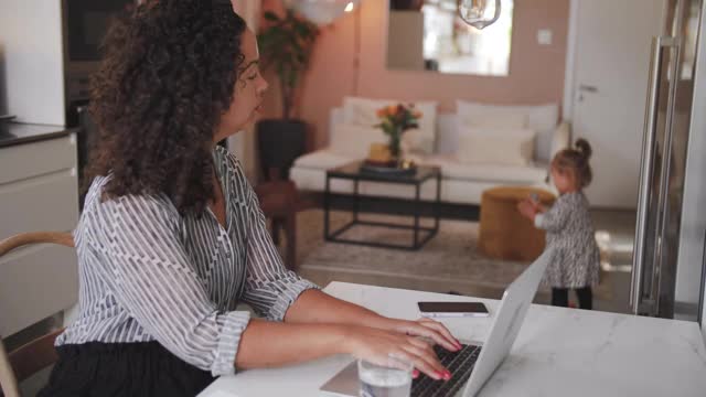 一头卷发的女商人在女儿在家玩的时候用笔记本电脑视频素材