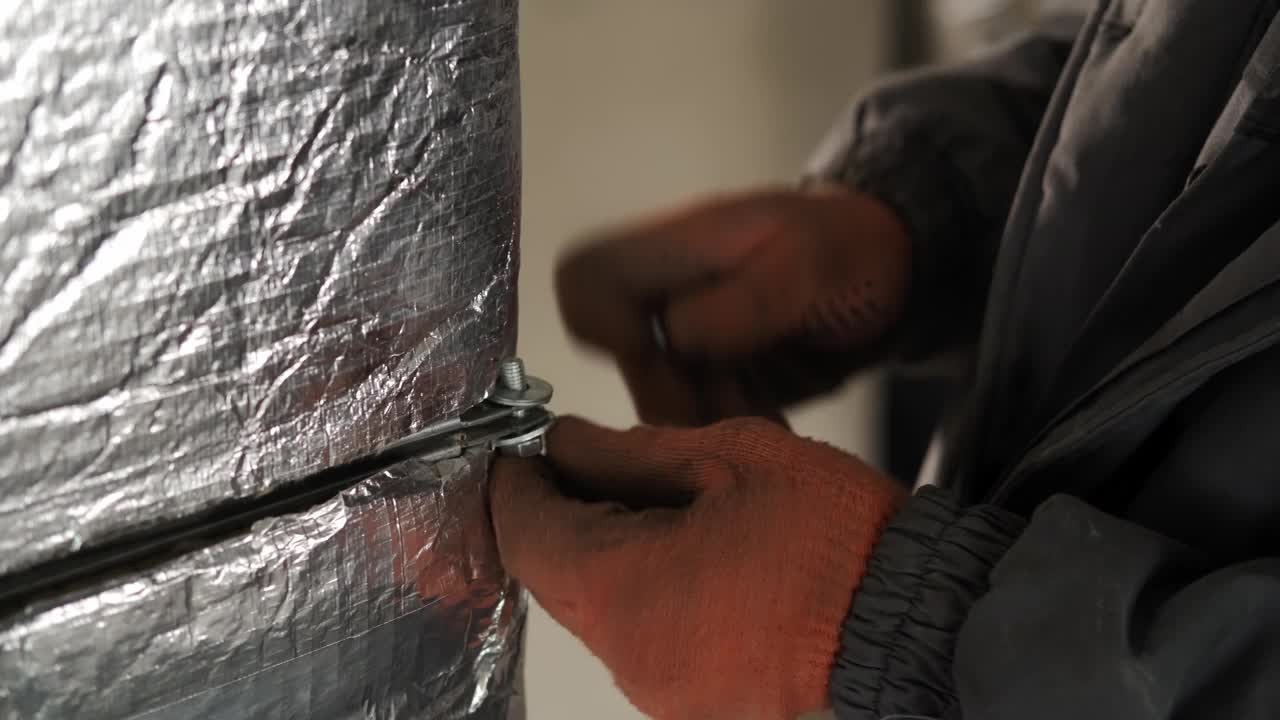 加热炉和集中采暖泵风管安装时，工人将物体上的螺栓拧紧。加热和冷却工作。视频下载