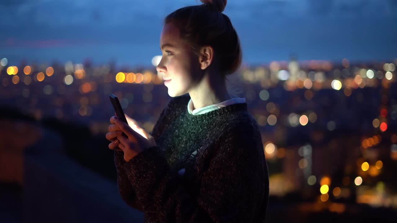 女人在晚上使用智能手机视频下载