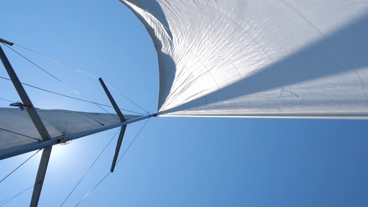 在公海上航行的帆船。风吹着游艇的白帆，阳光灿烂。概念:航海假期，自由视频素材
